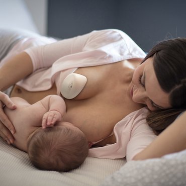 Mutter stillt ihr Kind liegend während der Ardo kindestCup an der anderen Brust haftet