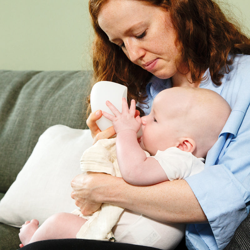 Mutter füttert ihr Baby mit Hilfe des Ardo kindestCup Fütterungsbechers